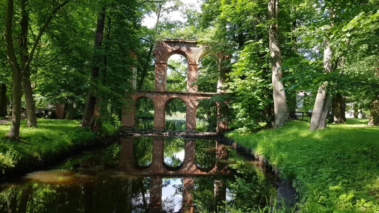 Ruiny mostu z cegły nad kanałem, otoczone zielenią. Idealne na weekendowe wycieczki, to jedne z fajnych miejsc niedaleko Warszawy.