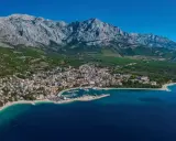 Widok na Baśkę Vodę z górami w tle. Atrakcje turystyczne obejmują plaże, port jachtowy i urokliwe miasteczko.
