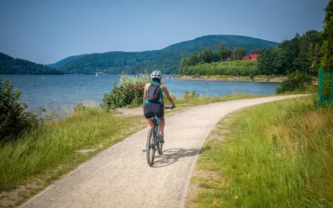 Kobieta na rowerze przemierza malowniczą ścieżkę nad jeziorem. Idealne miejsce, gdzie na rower!