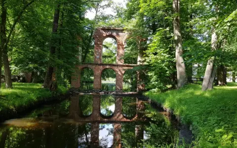 Ruiny mostu z cegły nad kanałem, otoczone zielenią. Idealne na weekendowe wycieczki, to jedne z fajnych miejsc niedaleko Warszawy.