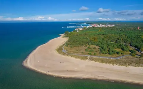 Piękna plaża i las na Helu. Warto zobaczyć to malownicze wybrzeże z portem i miasteczkiem w oddali.