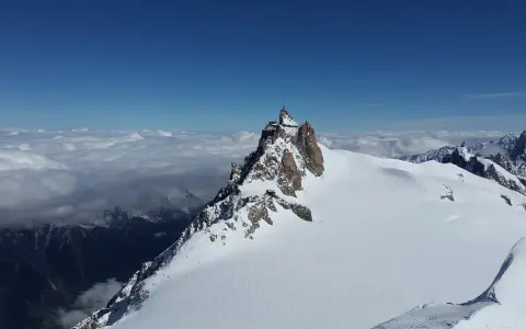 Szczyt Aiguille du Midi w Alpach Włoskich, z widokiem na morze chmur i ośnieżone góry.
