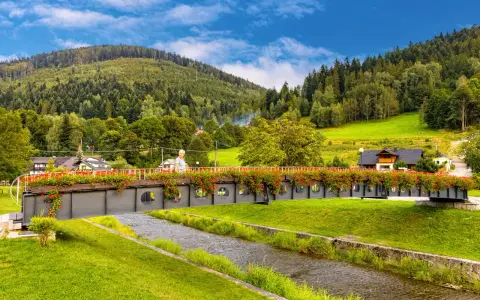 Piękny weekend w Szczyrku. Most ozdobiony czerwonymi kwiatami nad strumieniem, w tle góry i lasy.